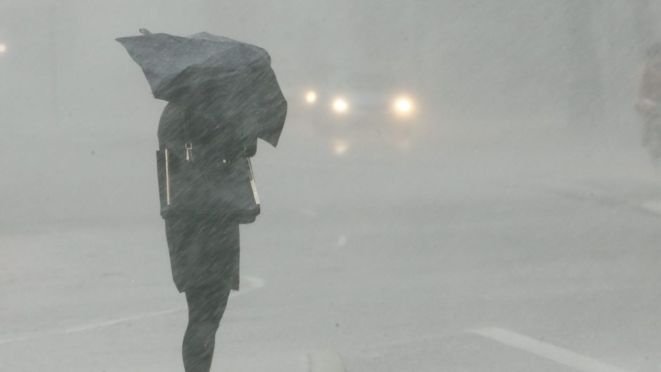 A woman waits to cross a street during a severe thunderstorm in Sydney.