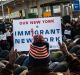 A group of Muslim men pray while supporters hold up signs during an interfaith prayer and rally against the ban at John ...