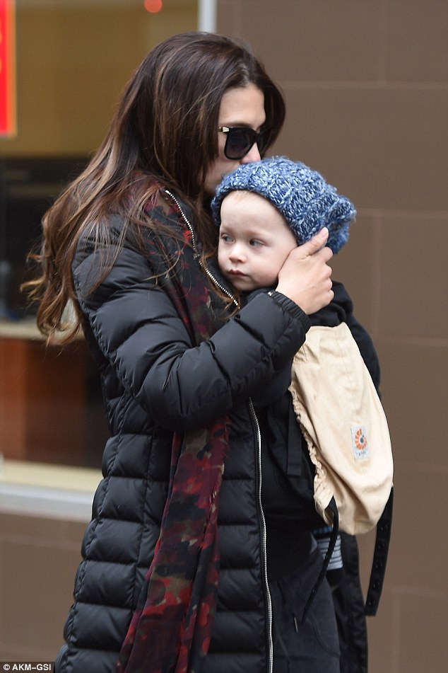 Precious moment: The yoga instructor was wrapped up warm in a padded jacket and joggers as she lovingly cradled her middle child