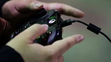 An attendee plays a video game on a Microsoft Corp. Xbox One video-game console at the Tokyo Game Show 2014 in Chiba, Japan, on Thursday, Sept. 18, 2014. Microsoft, maker of the Xbox video-game console, agreed to acquire Mojang AB, the software company behind the popular game Minecraft, for $2.5 billion, in a bid to boost its Xbox and mobile businesses. Photographer: Kiyoshi Ota/Bloomberg via Getty Images