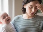 Young mother carrying baby and looking distressed