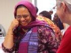 A woman laughing in conversation with another woman.