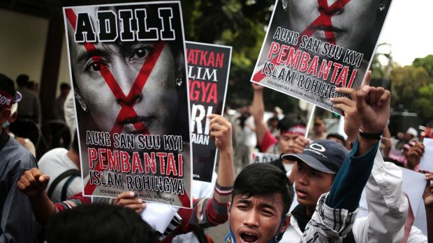 Protesters hold a defaced poster of Aung San Suu Kyi during a rally demanding justice for Rohingyas outside Myanmar's ...