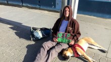 Man sleeping rough and his dog hold a sign