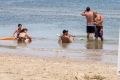 Port Melbourne beachgoers enjoy the water despite warning signs from EPA Victoria advising them not to.