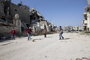 Syrian boys play soccer between destroyed buildings in the old city of Homs, Syria, Friday, Feb. 26, 2016.