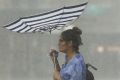 SYDNEY, AUSTRALIA - FEBRUARY 07: A woman crosses a street during a severe thunderstorm on February 7, 2017 in Sydney, ...