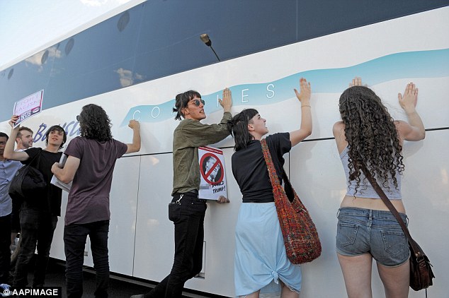 Protesters bang on the side of the bus being used to transport Q Society members