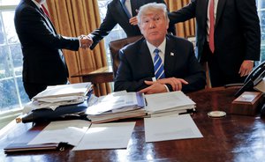 In this Wednesday, Feb. 8, 2017, file photo, President Donald Trump sits at his desk after a meeting with Intel CEO Brian Krzanich, left, and members of his staff in the Oval Office of the White House in Washington.