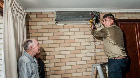 Air conditioning installer Bill Skourtis, right, works in 39-degree heat to help Joe Moore, left, keep cool.