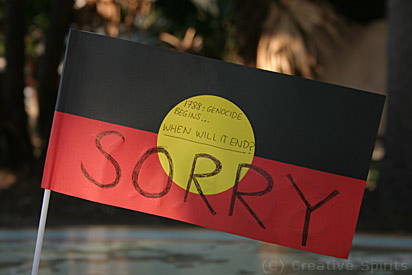 An Aboriginal flag with the words '1788: Genocide begins…when will it end? Sorry.'.