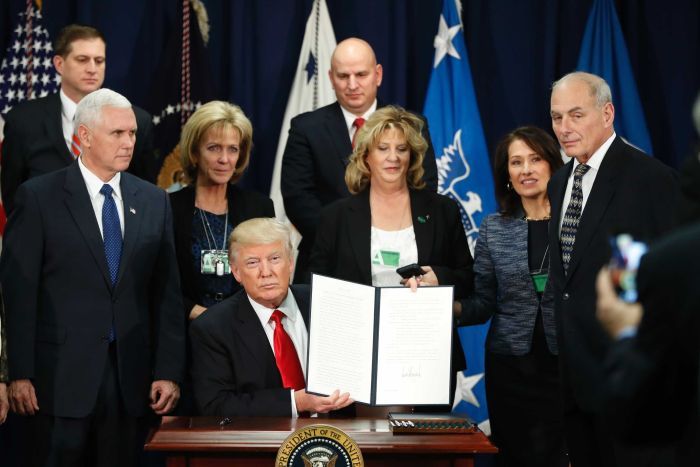 President Donald Trump, with Vice President Mike Pence, holds up an executive order on the Mexico border wall, January 25, 2017.