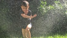 A child plays in the sprinkler