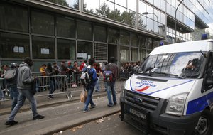 File - A police van parks as refugees queue outside a refugees center in Paris, France, Friday Aug.5, 2016.