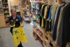 A woman holds a pair of green and gold Aussie shorts in front of her inside a small shop.