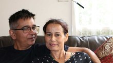 Desiree and Leslie Lobo sitting together on a couch in their home.