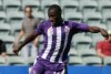 Million Butshiire wearing the Perth Glory colours in action coming up to kick a ball.