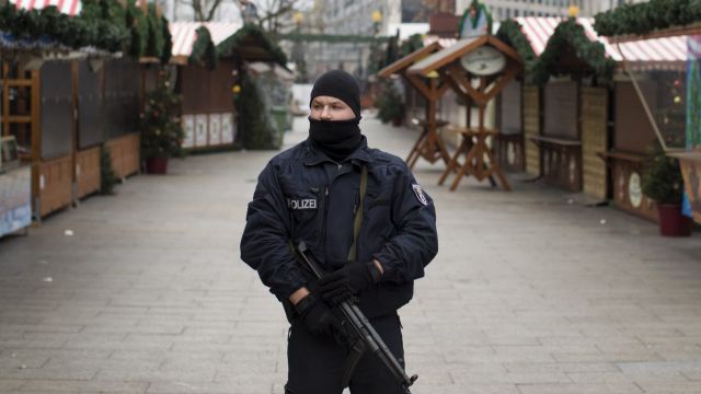 An armed police officer stands guard as the festive stalls remain closed at Berlin Christmas market in Berlin, Germany ...