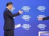 China's President Xi Jinping stretches his arm towards WEF founder Klaus Schwab, right, after his speech at the World Economic Forum in Davos, Switzerland, Tuesday, Jan. 17, 2017.