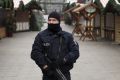 An armed police officer stands guard as the festive stalls remain closed at Berlin Christmas market in Berlin, Germany ...