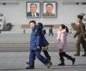 Children walk past portraits of late North Korean leaders Kim Il Sung and Kim Jong Il at the Kim Il 