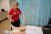 A woman in a red shirt performs healing touch on a man who is lying down