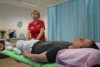 A woman in a red shirt performs healing touch on a man who is lying down