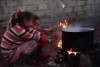 Two children warm themselves by a fire