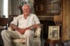 David Manning at home in Ballarat sitting on an armchair with a picture of him as a young 13-year- old in navy attire. 