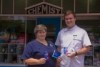 A woman in a nurses' uniform and man in pharmacist's white shirt standing outside an old shop front with the word chemist on it