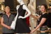 Two women standing next to mannequins in a women's clothing section of a department store