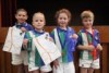 Four children with awards smile at the camera.