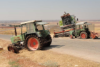 Tractors with graffiti and busted tyres sit derelict on the roadside in Syria with untended brown fields behind