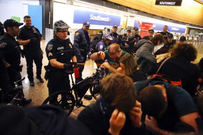 Seattle police use pepper spray and push the last group of protesters out of a Seattle airport terminal