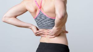 Close up Athletic Woman Holding her Painful Injured Back While Doing an Exercise.