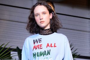 Model walks for Creatures of Comfort wearing a 'We are all Human Beings' sweater, expressing unity of all people.