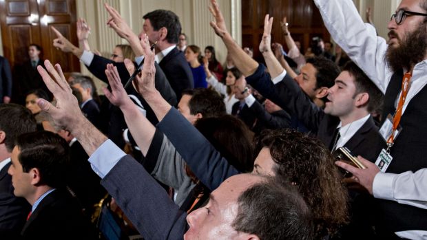 Members of the media raise their hands to ask a question of Donald Trump.