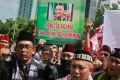 Protesters shout slogans as they hold up a placard depicting Jakarta governor Basuki Tjahaja Purnama behind bars in Jakarta.