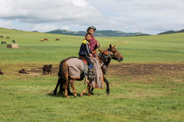A nomadic man teaches his son how to ride a Mongolian Horse on the steppes of central Mongolia.
