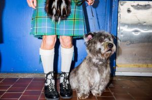An owner wearing a kilt stands with his Glen of Imaal Terrier 