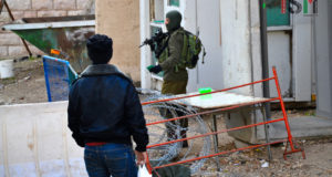 Palestinian man is kept waiting for several minutes in front of the checkpoint, as israeli forces are checking his ID, violating his freedom of movement.