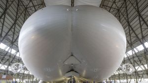 Workers and media stand under the front of the hull of the Airlander 10 hybrid airship, manufactured by Hybrid Air ...