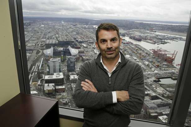 Chris Hansen, the investor hoping to build an arena to house a possible NBA basketball or NHL hockey franchise in Seattle's stadium district, poses for a photo in front of a window showing CenturyLink Field, the home of the NFL football Seattle Seahawks, and Safeco Field, the home of the MLB baseball Seattle Mariners, Thursday, Feb. 16, 2017, in downtown Seattle. Hansen stressed patience and optimism with his ongoing effort to get the arena built in an interview with The Associated Press.