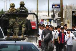 A patrol of Mexican Marines pass by a group of young men on their way to a rally for Tamaulipas gebernatorial PAN candidate Baltazar Hinojosa Ochoa in Reynosa, Wednesday, April 6, 2016. Security in the city that has no police department has become a major political issue.