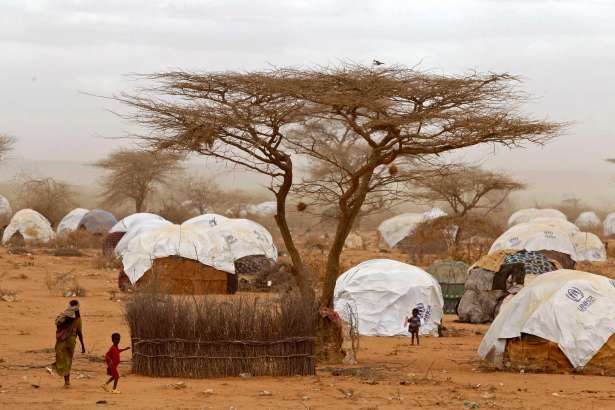 FILE - In this Thursday, Aug. 4, 2011 file photo, refugees walk amongst huts at a refugee camp in Dadaab, Kenya. About 140 Somali refugees whose resettlement in the United States this week was stopped by President Donald Trump's executive order have been sent back to Dadaab refugee camp in northern Kenya, one of the refugees said Saturday, Feb. 4, 2017.