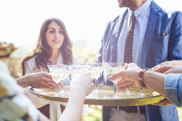 Man holding tray of drinks, group of friends reaching for drinks champagne sparking wine