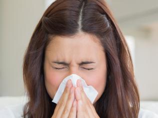 Brunette sneezing in a tissue