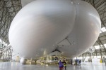 Workers and media stand under the front of the hull of the Airlander 10 in Bedford, Britain.