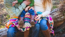 Parents cuddle a child sitting in their lap.