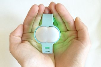 A woman holds the Ava fertility tracking bracelet.